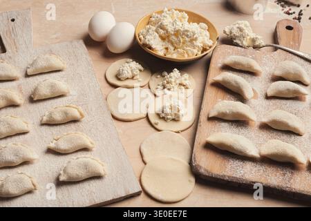 Processo di cottura dei guanciali con ripieno di formaggio su tavole di legno in cucina Foto Stock