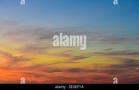 Cielo serale moodico caratterizzato da un profondo sfondo indaco con delicate formazioni di nuvole rosa artistiche che ricordano tratti di vernice ad acquerello al tramonto. Foto Stock