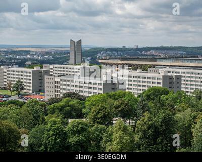 Grandi blocchi di appartamenti bianchi e Monumento Monolitico in cemento sopra gli alberi verdi sotto il cielo nuvoloso, Praga, Repubblica Ceca. Foto Stock