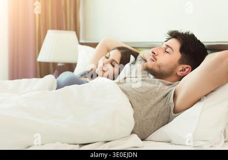 Giovane coppia che dorme sul letto in camera da letto Foto Stock