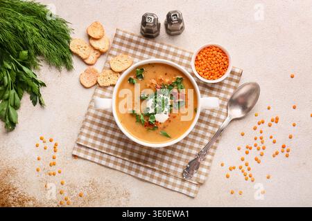 Pentola di gustosa zuppa di lenticchie e crostini su sfondo beige grunge Foto Stock