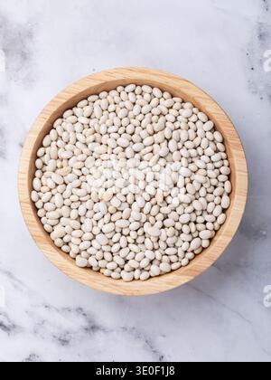 Fagioli bianchi in un recipiente di legno sul tavolo, vista dall'alto Foto Stock