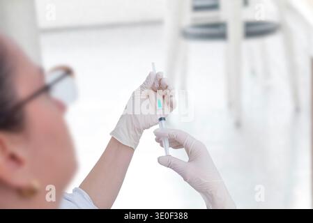 Operatore sanitario che prepara la siringa con il vaccino prima della procedura di iniezione in ambiente clinico medico Foto Stock