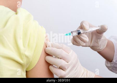 Primo piano del medico che inietta il vaccino nel braccio del paziente in clinica durante la procedura di vaccinazione medica Foto Stock