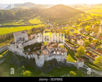 Le rovine del castello di Rabi sorgono maestosamente circondate da lussureggianti campi verdi e pittoreschi villaggi. La prospettiva aerea cattura le dettagliate strutture in pietra illuminate dalla luce dorata del tramonto. Foto Stock