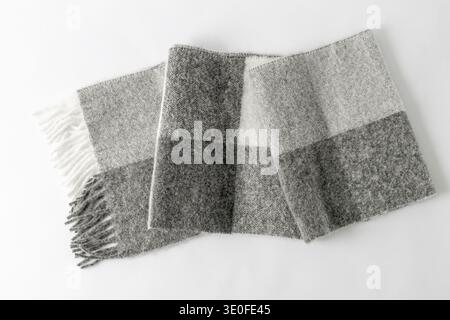 Sciarpa calda e soffice in misto lana di alpaca con effetto cromatico. Scialle di colore grigio crema piegato su sfondo neutro chiaro. Foto Stock