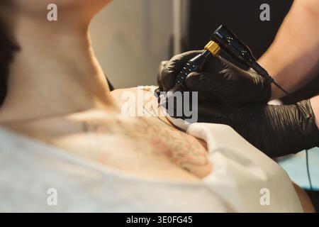 Tatuatore che lavora con ago sul corpo dei clienti Foto Stock