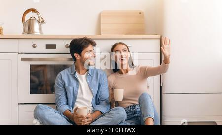 Una coppia si diverte insieme in cucina mentre condivide storie e sorrisi Foto Stock