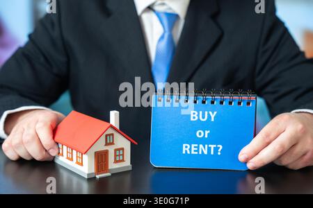 Casa con le parole affittare o comprare in mani maschili. Concetto immobiliare. Affittare un appartamento. Casa in affitto. Acquisto o acquisto di alloggi. Svolta a destra Foto Stock