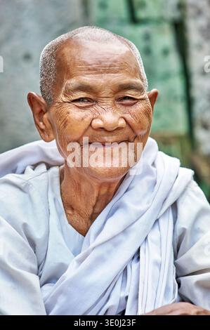 Una donna anziana sorride mentre indossa una veste bianca a Siem Reap, Cambogia. Le piace un momento di felicità nell'ambiente circostante. Foto Stock