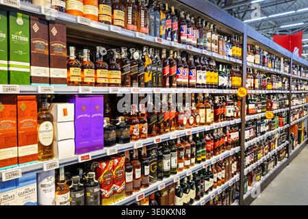 Ampia scelta di bottiglie di whisky e scotch sugli scaffali dell'ipermercato Auchan Foto Stock
