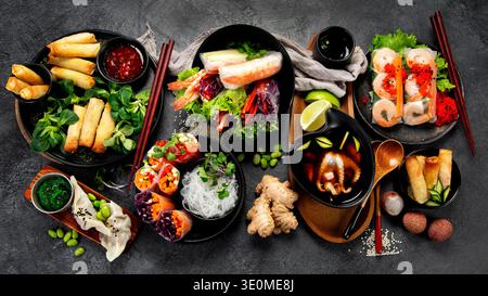 Vari involtini primaverili vietnamiti riempiti con vari ingredienti freschi come verdure, spezie, carne o gamberetti su sfondo scuro. Vista dall'alto. Foto Stock