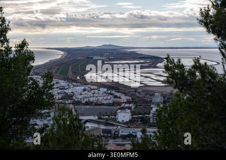 Vista elevata dal Mont Saint-Clair sulla costa mediterranea vicino a Sète, con paludi lagunari, campi e nuvole spettacolari a Occitanie, Francia. Foto Stock