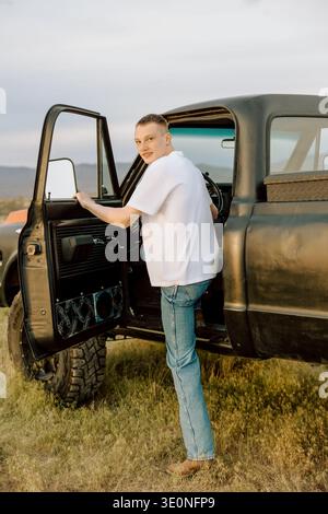 Giovane in piedi davanti alla porta del camion aperta all'aperto Foto Stock