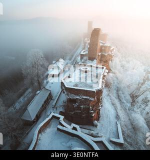 Vista aerea delle rovine del castello di Dahn, un netto contrasto con il paesaggio innevato e la nebbia eterea, Dahn, Rheinland-Pfalz, Germania. Foto Stock
