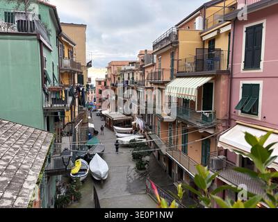 Manarola, cinque Terre, Italia. La tradizionale e colorata architettura ligure è allineata a una stretta strada dove sono conservate le piccole barche. Foto Stock