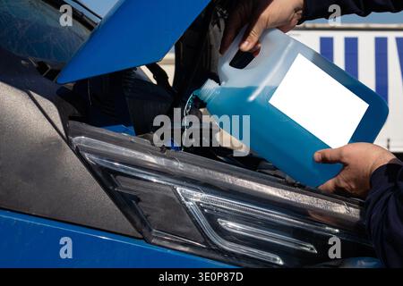Processo di manutenzione per l'aggiunta di liquido lavavetri a un veicolo per garantire la pulizia dei finestrini durante la marcia e la guida. Foto Stock
