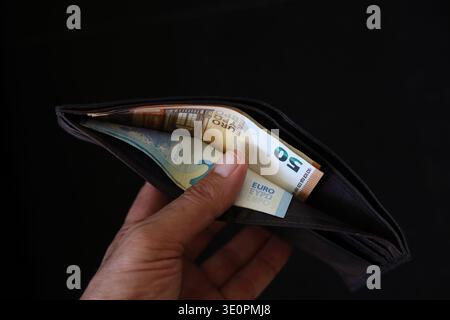 soldi in un portafoglio su sfondo nero. mano che mostra il portafoglio aperto con euro Foto Stock
