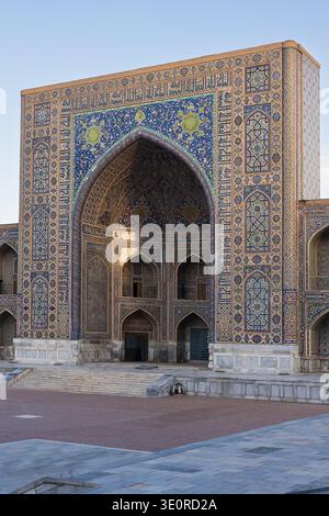 Madrasa Tillya Kari - arco principale, primo piano, dettagli all'alba - architettura islamica timuride - piastrelle a mosaico turchese alla luce del sole dorata, cielo blu acceso Foto Stock