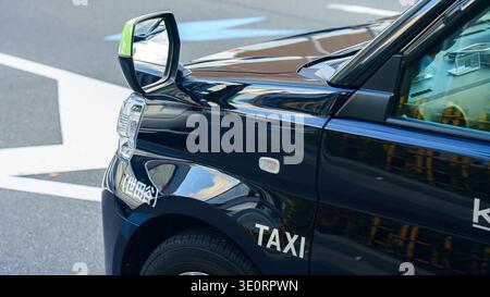 Tokyo, Giappone - 14 ottobre 2024, vista ravvicinata di una parte del cofano, specchio laterale di un taxi nero, con la scritta "taxi", nel quartiere Ginza, Tokyo Foto Stock