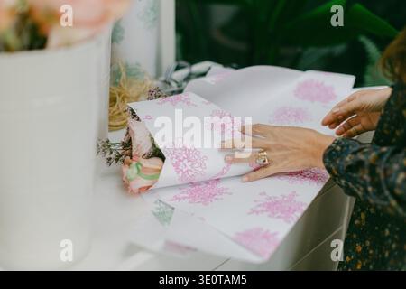 Involgere fiori con carta decorativa su un tavolo in un ambiente domestico durante il giorno per un'occasione speciale Foto Stock