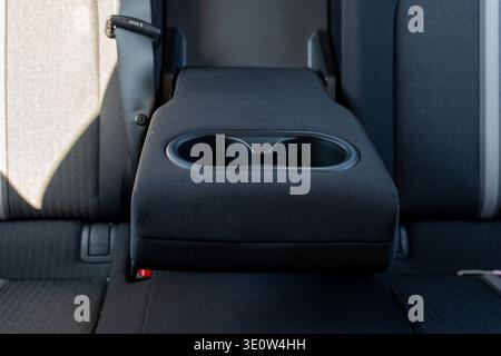 Bracciolo del sedile posteriore con portabicchieri – interno orizzontale della vettura, concetto di comfort dei passeggeri Foto Stock