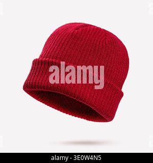 Berretto invernale a maglia rosso intenso che galleggia nell'aria su sfondo pastello chiaro. Concetto di intimo stile stagionale, accessori caldi, stile informale Foto Stock