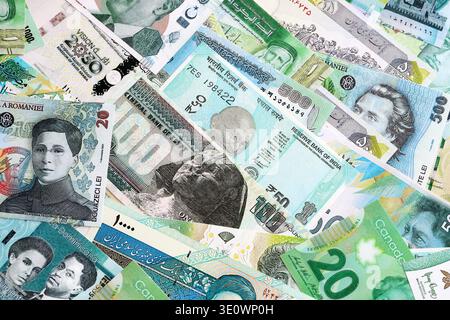 Varie valute banconote banconote di colore verde. Molte banconote in contanti da diversi paesi in grande pila da vicino. Economia mondiale e concetto di cambio valuta Foto Stock