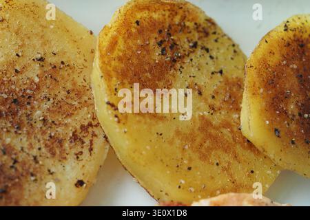 Fette di patate cotte con condimento su un piatto Foto Stock