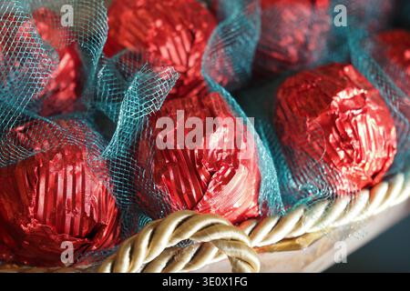 Tartufi di cioccolato in involucri rossi posti in un cestino Foto Stock