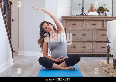 Stretching, sostegno o donna incinta sul tappetino da yoga in casa, mobilità muscolare o sollievo da tensione per le articolazioni. Toccare lo stomaco, l'esercizio di maternità o la persona Foto Stock
