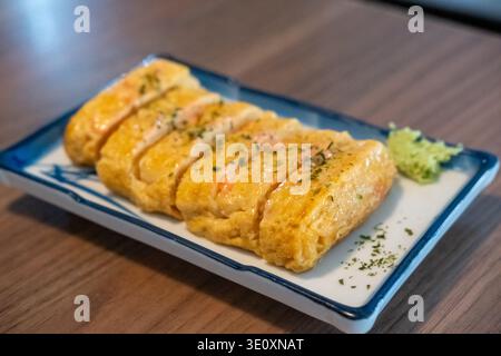 Tamagoyaki, un'omelette giapponese preparata arrotolando diversi strati di uova sbattute fritte, servita su un piatto. Foto Stock