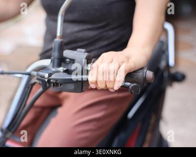 Un'immagine ravvicinata di una persona che preme l'acceleratore di una motocicletta. Foto Stock