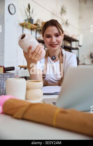 Felice donna caucasica che tiene un vaso di ceramica in uno studio di ceramica Foto Stock
