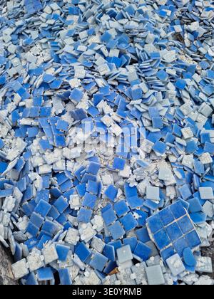 Primo piano di molti pezzi quadrati di ceramica blu e grigio chiaro scaricati in massa. Sfondo astratto che simboleggia lavori di ristrutturazione, riciclaggio di materiali o cre Foto Stock