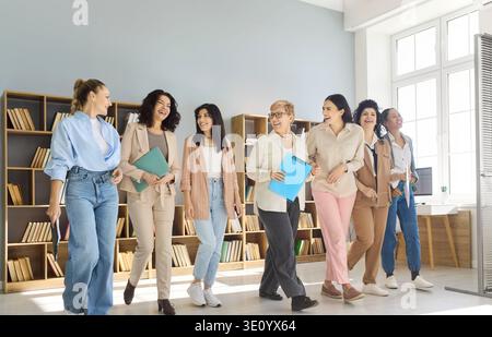 Team di donne d'affari sicure e diversificate che camminano insieme attraverso i moderni uffici Foto Stock