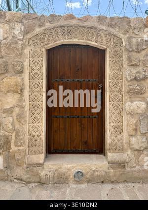 Porta d'ingresso della tradizionale casa di pietra mediorientale. Porta in legno battuto in ferro su una strada della città mediorientale. Strade di Mardin, Turchia Foto Stock