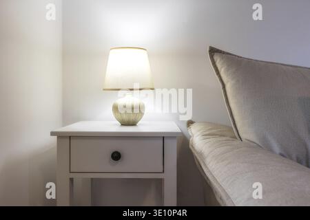 Lampada per camera da letto su un comodino accanto al divano, primo piano Foto Stock