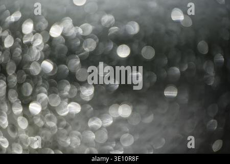 Immagine artistica astratta con scintillanti bokeh color argento che creano una texture visiva eterea ed elegante, questo versatile sfondo evoca la sophistica Foto Stock