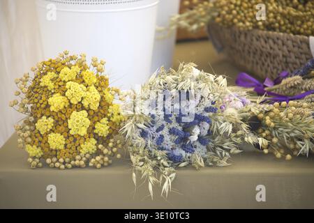 Primo piano di vivaci mazzi di fiori secchi in tonalità di giallo, bianco e blu, creando una disposizione floreale rustica e affascinante Foto Stock