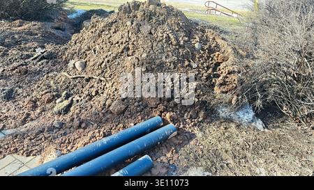 Sito di scavo con tubi di pubblica utilità in plastica e pali di terreno per l'installazione di condotte sotterranee Foto Stock