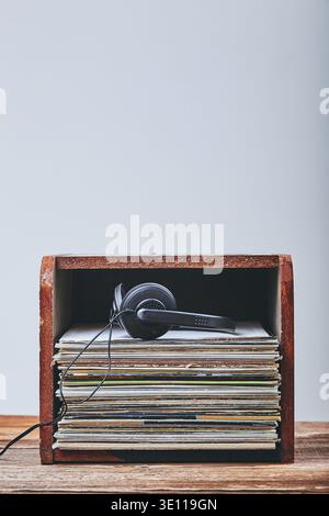 Una pila di molti dischi in vinile nero e cuffie posizionate in cima alla pila. Persone since, momenti reali, situazioni autentiche Foto Stock