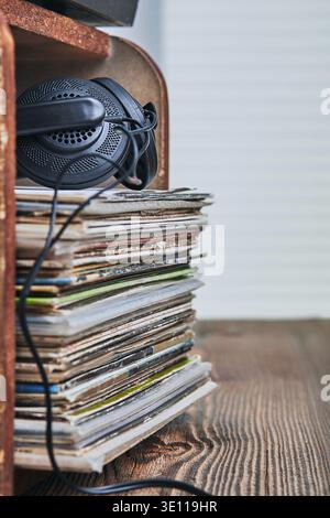 Una pila di dischi in vinile nero e cuffie sulla parte superiore. Persone since, momenti reali, situazioni autentiche Foto Stock