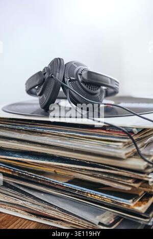 Una pila di dischi e cuffie in vinile nero sulla parte superiore dello stack. Persone since, momenti reali, situazioni autentiche Foto Stock