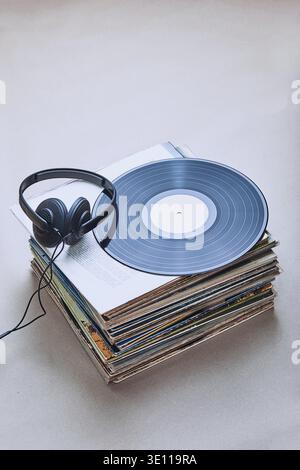 Stack di molti dischi in vinile nero, cuffie sulla parte superiore dello stack. Persone since, momenti reali, situazioni autentiche Foto Stock