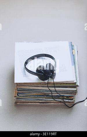 Stack di molti dischi in vinile nero, cuffie sulla parte superiore dello stack. Persone since, momenti reali, situazioni autentiche Foto Stock