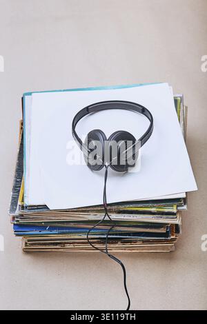 Stack di molti dischi e cuffie in vinile nero sulla parte superiore dello stack. Persone since, momenti reali, situazioni autentiche Foto Stock