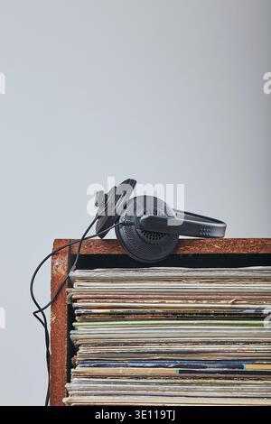 Una pila di molti dischi in vinile nero e cuffie posizionate in cima alla pila. Persone since, momenti reali, situazioni autentiche Foto Stock