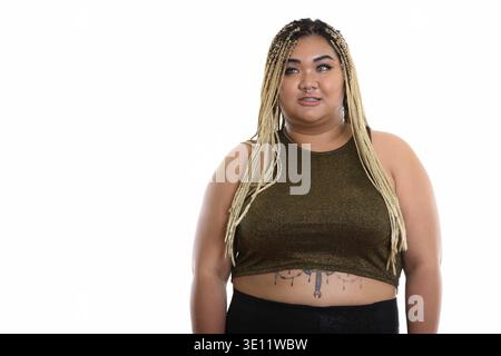 Studio shot di giovani felici fat donna asiatica sorridere mentre pensando Foto Stock