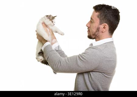 Vista di profilo del giovane bello uomo caucasico holding cat isolata contro uno sfondo bianco Foto Stock